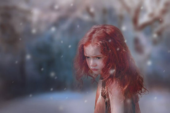 Ein kleines rothaariges Mädchen in einer Schneelandschaft.